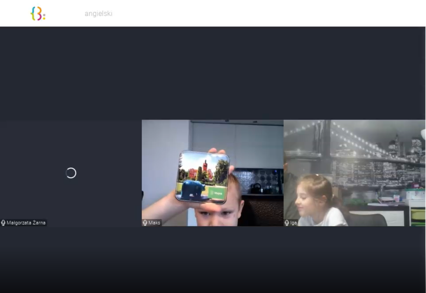 Screen ze spotkania na&nbsp;platformie Clickmeeting. Ekran podzielony jest na&nbsp;3 części: po lewej widać czarny prostokąt ze znakiem ładowania, po środku około 5-letniego chłopca, który pokazuje kwadratową podkładkę ze słupskim ratuszem i&nbsp;niedźwiadkiem szczęścia, po prawej widać około 7-letnią dziewczynkę obróconą prawym bokiem do ekranu